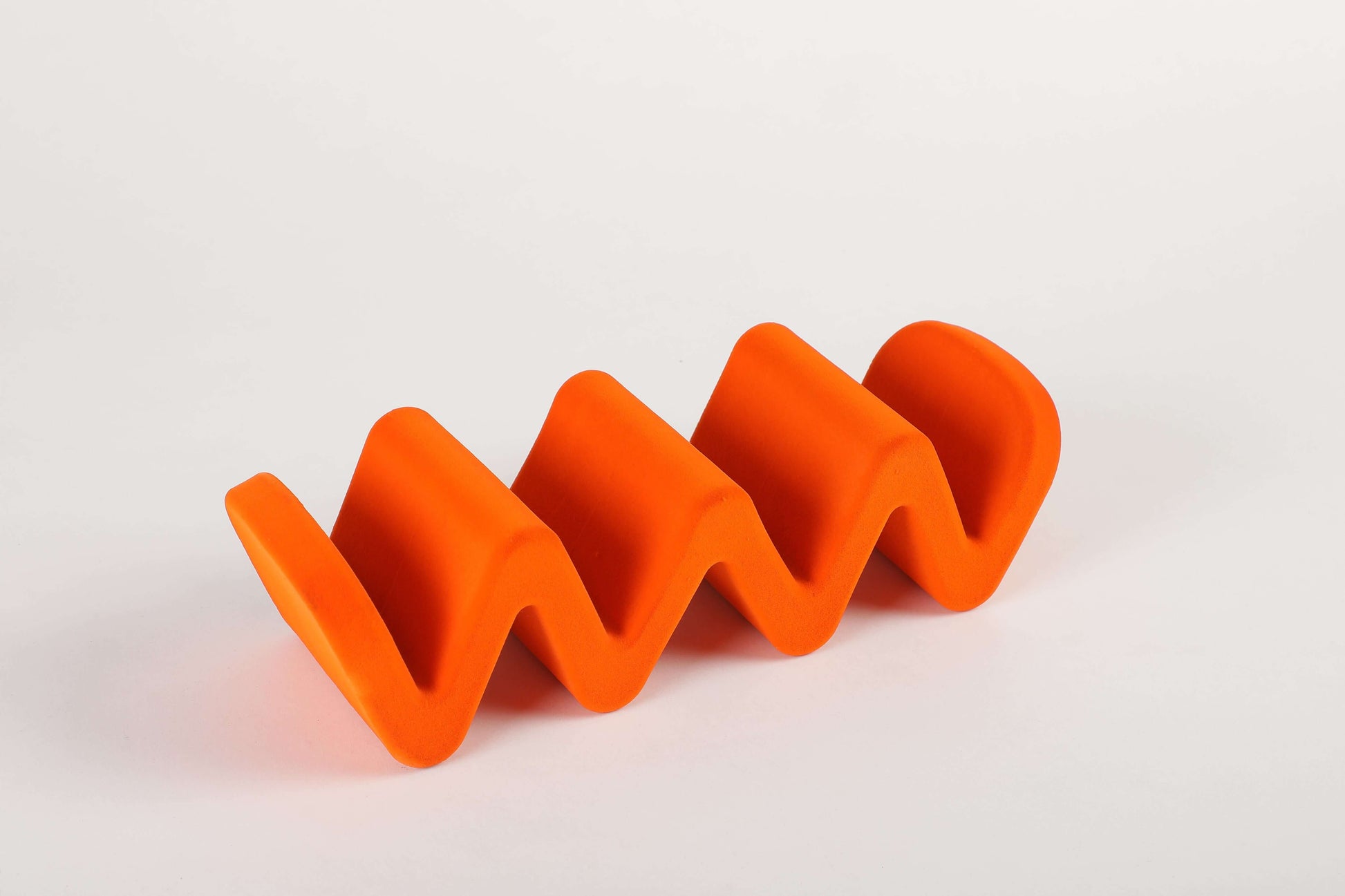 W-shaped orange Wave Organiser with soft velvet finish for a clutter-free workspace. Fun and quirky desk accessory for organization.